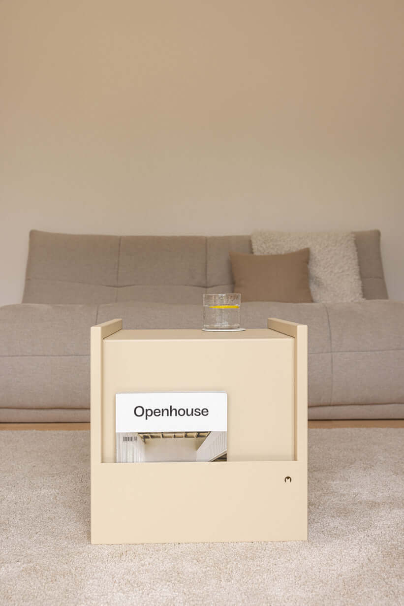 Beistelltisch in modernem beige Design mit Zeitschrift und Glas auf einem hellen Teppich.