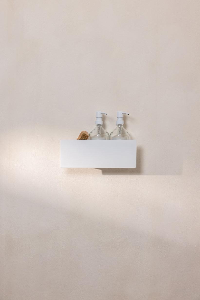 Duschablage SHEA aus Aluminium mit zwei transparenten Flaschen auf einer Wand, modernes und stilvolles Design.