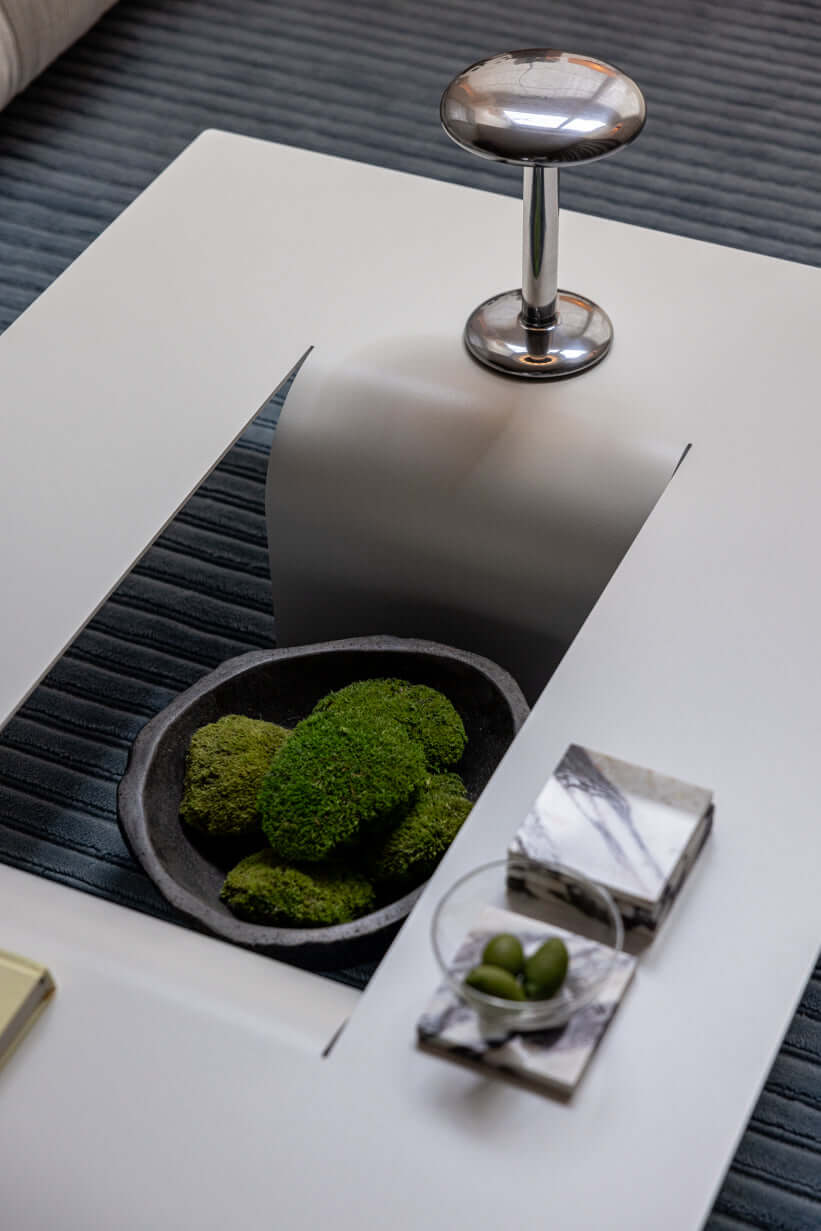 Modern Couchtisch mit zentraler Öffnung und dekorativem Moos, minimalistisches Design aus Metall.