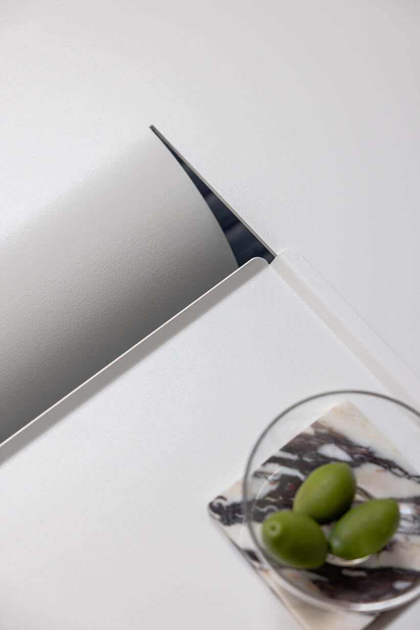 Detailansicht des modernen Couchtischs CUT mit eleganter Kante und einer Schale mit Oliven.