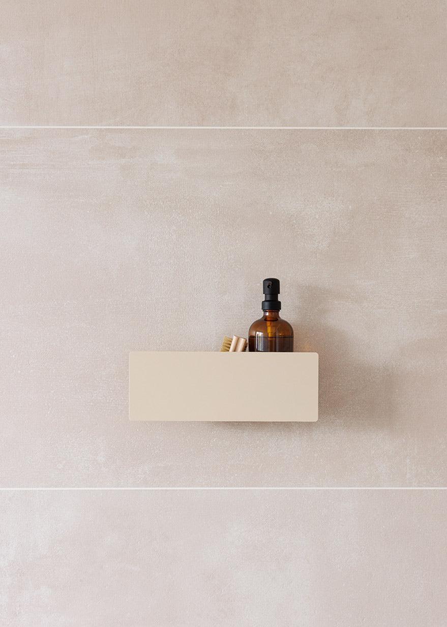 Duschablage SHEA an einer Wand mit einem braunen Fläschchen und Holzutensilien darauf.